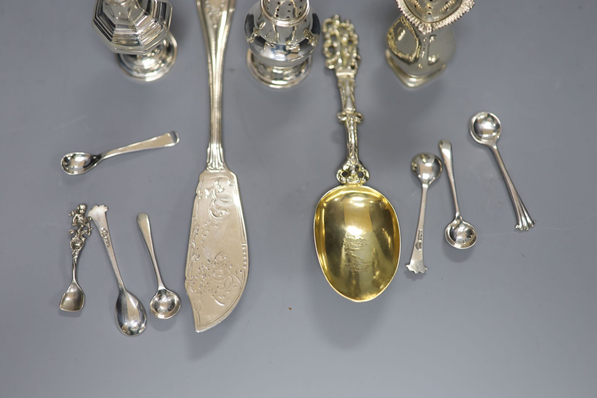 A Victorian silver butter knife, an ornate Dutch white metal spoon, seven condiment spoons including six silver, one 835 & 3 peppers.